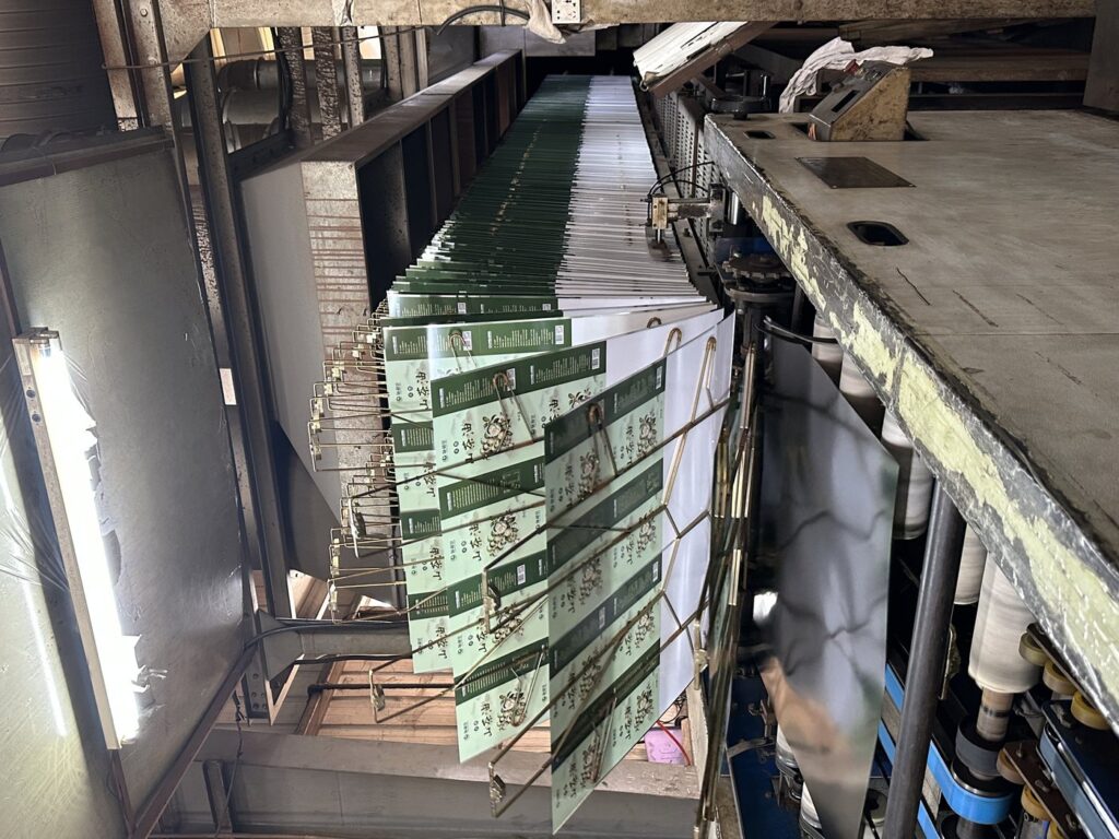 Printed tinplate sheets entering the oven-drying stage at Junmei